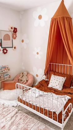 a bedroom with an orange canopy bed and pink pillows on the floor, along with two teddy bears