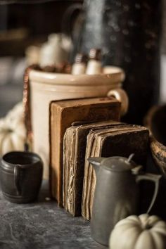 an old book, coffee pot, and other items on a table with pumpkins