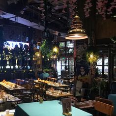 an empty restaurant with tables and chairs in front of the window, surrounded by hanging plants