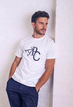 a man leaning against a wall wearing a white t - shirt with the letters apc on it