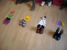 several children's shoes are arranged on the floor with paper animals and umbrellas