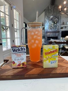 a pitcher of orange juice, carton of starburst and two packets of steaduras on a cutting board