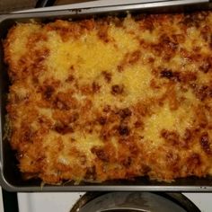 a casserole dish sitting on top of a stove next to a pan filled with food