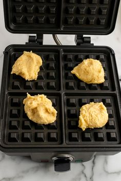 four waffles are being cooked in a pan on a marble counter top,