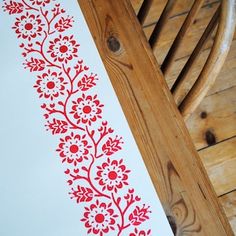 a red and white floral design is on the floor next to a wooden rocking chair