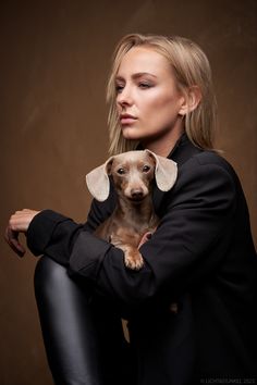 a woman is holding a small dog in her lap and posing for the camera,