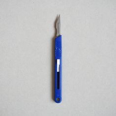 a blue and silver pen sitting on top of a white table next to a knife