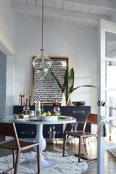 the dining room table is surrounded by two chairs and an art piece on the wall