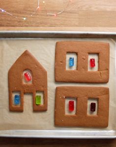 three gingerbread houses on a pan with candy in the shape of windows and doors