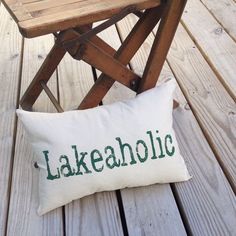 a wooden chair sitting on top of a wooden floor next to a pillow that says lakeaholic