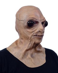 an alien man with large black eyes wearing a black t - shirt and looking at the camera