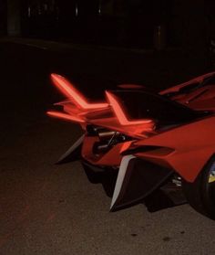 a red sports car parked on the side of the road at night with it's door open