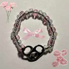 a pair of black scissors sitting on top of a pink beaded bracelet next to a flower