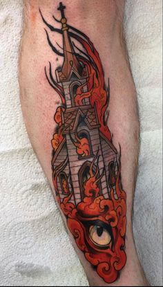 a man's leg with a tattoo on it that has flames coming out of the building