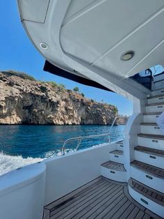 the view from inside a boat looking out at an island and blue water with cliffs in the background