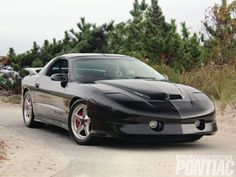 the black sports car is parked on the side of the road in front of some trees