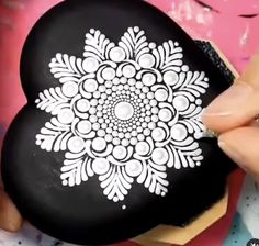 someone is painting a black and white flower on a rock