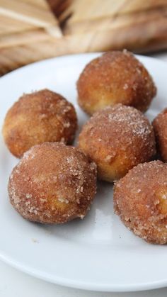 some sugared doughnuts are on a white plate