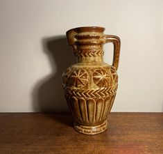 a brown vase sitting on top of a wooden table