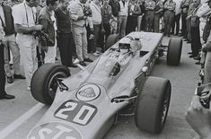 a man driving a race car in front of a group of people on the street