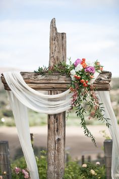 a wooden cross decorated with flowers and greenery