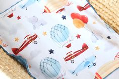 a baby blanket with hot air balloons and stars on it sitting in a wicker chair