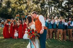 a bride and groom kissing in front of their wedding party at the end of an outdoor ceremony