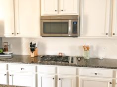 a stove top oven sitting inside of a kitchen next to white cupboards and counter tops