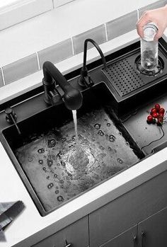 a person is pouring water into a sink with red flowers on the bottom and black faucet