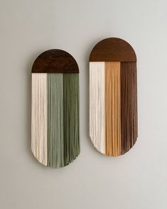 two wall hangings made out of wood and different colored fringes on each side