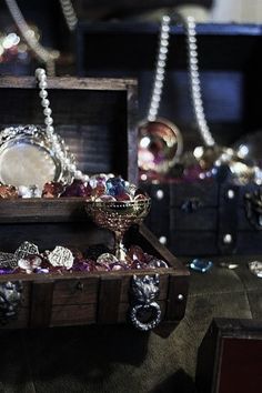 an assortment of jewelry on display in a wooden box with beads and chains hanging from it