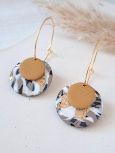 a pair of earrings with a wooden disc hanging from the front and back of it