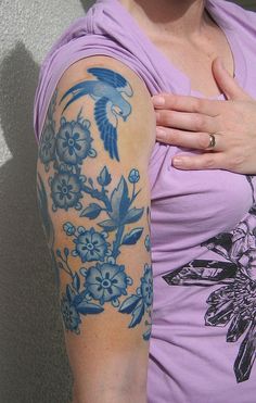 a woman with a tattoo on her arm and shoulder is posing for the camera while wearing a purple shirt