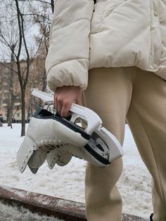 a person holding a pair of gloves in their hand while walking on the snow covered ground