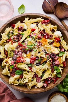 a wooden bowl filled with pasta salad on top of a table