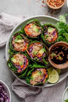 a white plate topped with lettuce wrapped in meat and garnished with cilantro