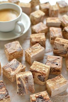 small pieces of food sitting on top of a table next to a cup of coffee