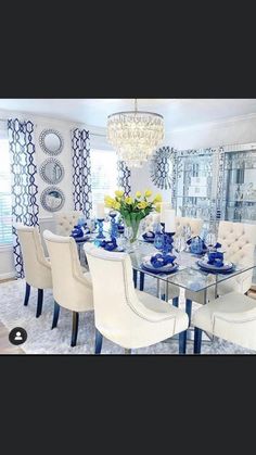 the dining room table is set with blue and white plates, silverware, and flowers