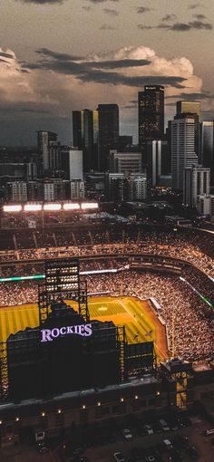 an aerial view of a baseball stadium with the city skyline in the background at night