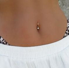 a close up of a person wearing a white top and gold necklace with a pearl on it