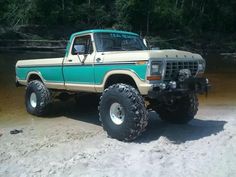 a large truck parked on top of a sandy beach next to a body of water