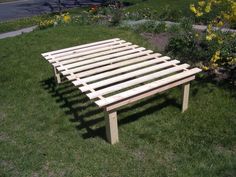 a wooden bed frame sitting in the grass