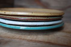 a stack of three plates sitting on top of a wooden table next to each other