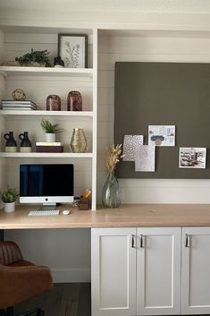 a home office with white cabinets and shelves