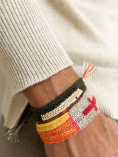 a person wearing four different bracelets on their arm and one has a cross on it