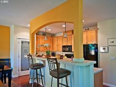 a kitchen with yellow walls and bar stools