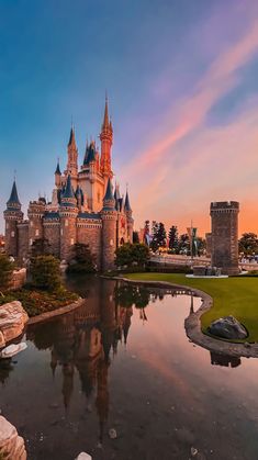 an image of a castle with water in the foreground and sunset in the background