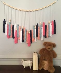 a teddy bear sitting next to a book and some tassels on the wall