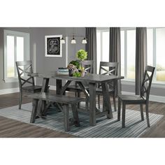 a dining room table with chairs and a bench in front of the window on a rug