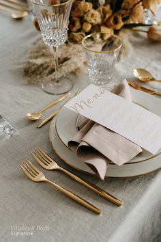 a table set with silverware and gold place settings